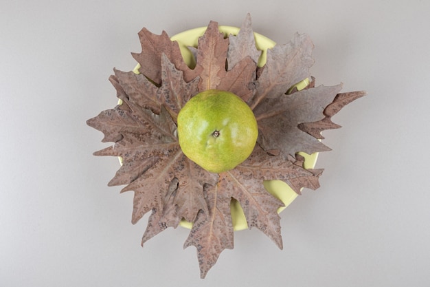 Free photo pear on plane tree leaves on marble