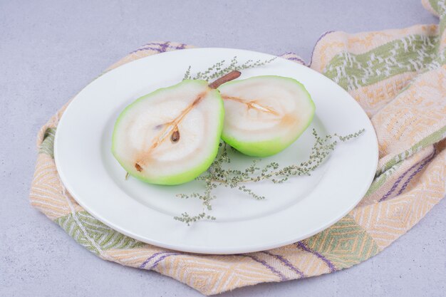 Ломтики груши с зеленью в белой тарелке