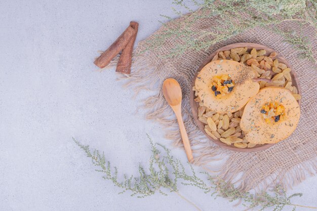 Pear slices with sultanas and cinnamon sticks in a wooden plate