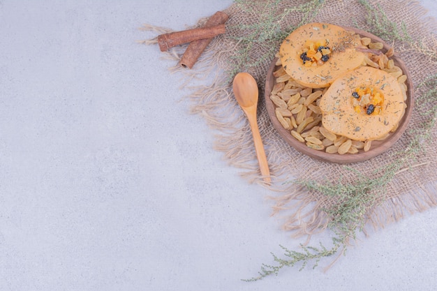 Pear slices with sultanas and cinnamon sticks in a wooden plate