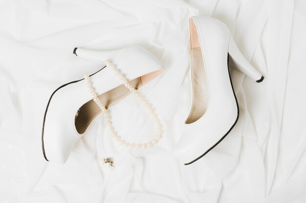 Pearl necklace and earrings with pair of wedding high heels on scarf