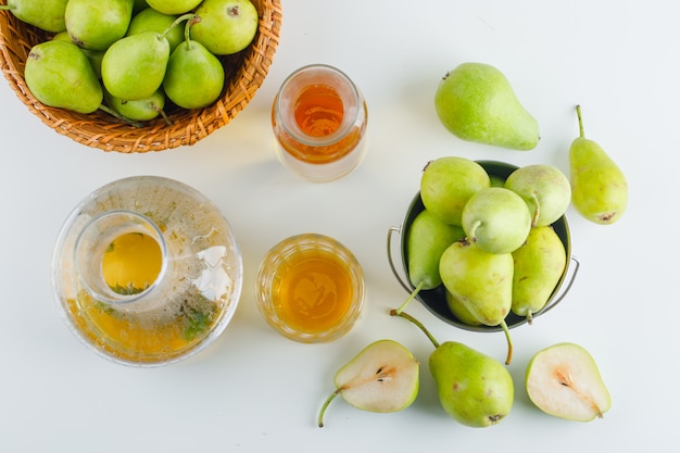 Pears in basket and bucket with drink flat lay on a white table