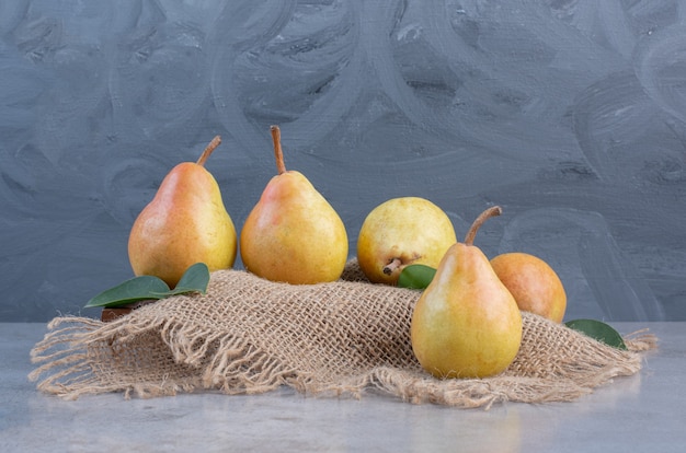 Pears on a board covered with a piece of cloth on marble background. 