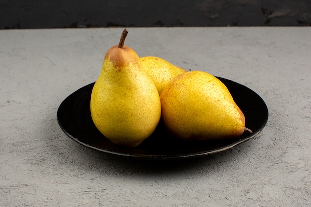 Pears fresh ripe mellow inside black plate on a light