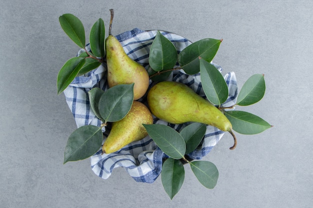 Pears and leaves in a bowl covered with a towel on marble 