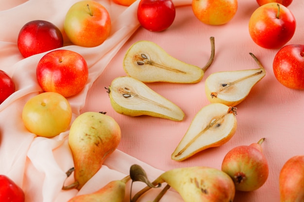 Pears and plums high angle view on pink and textile suruface