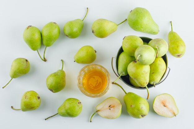 Free photo pears with drink in a mini bucket on white surface, flat lay.