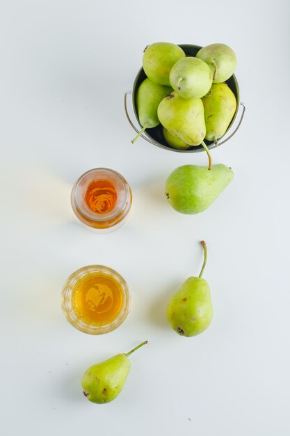 Pears with drink in a mini bucket on white surface, top view.