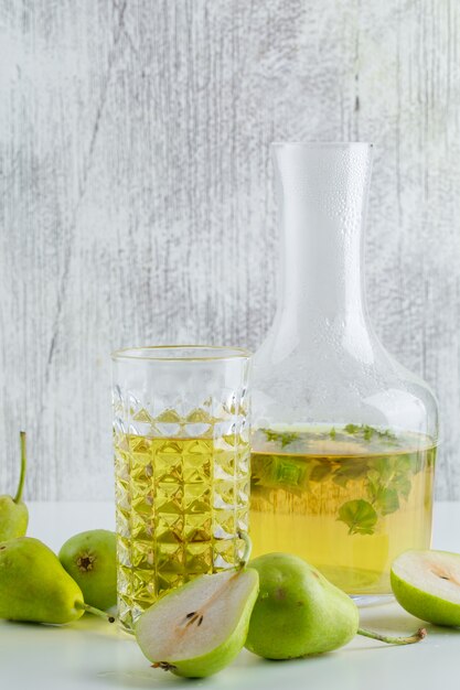 Pears with herbal drink on white and grungy wall, side view.