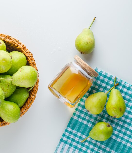 Pears with honey in a basket on white and kitchen towel, flat lay.