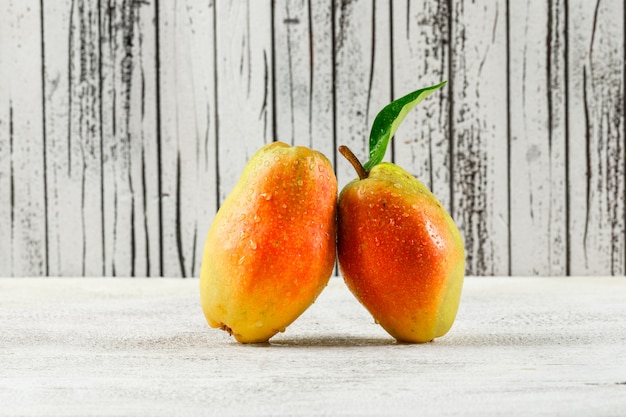 Free photo pears with leaf on grungy wooden and white background.