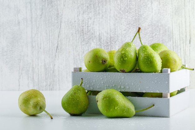 Pears in a wooden box side view on white and grungy background