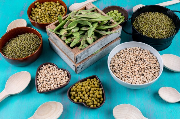 Peas and beans in wooden box, bowls with spoons