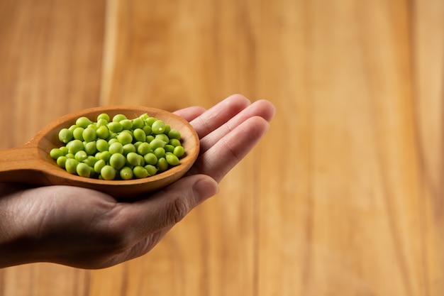 Free photo peas place a wooden spoon on your hand.