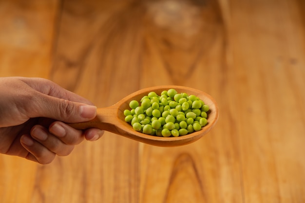 Free photo peas place a wooden spoon on your hand.