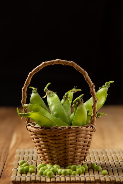 Peas placed in a woven wooden basket on a wooden table