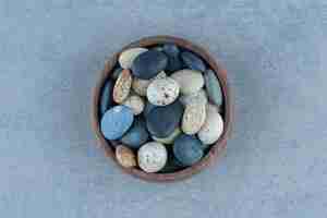 Free photo pebble stone candies in a bowl, on the marble table.