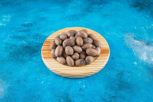 Pecan nuts on a wooden plate , on the blue table. 