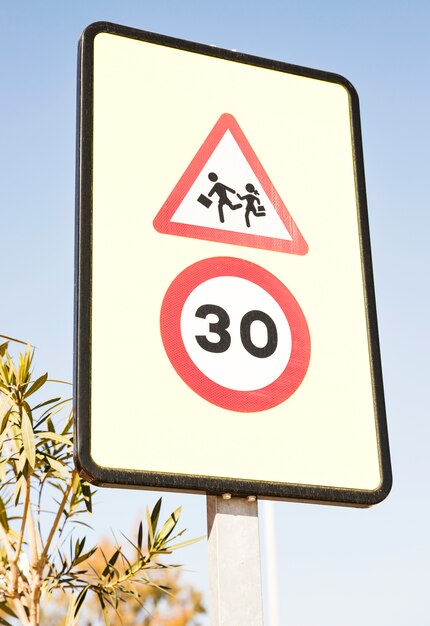 Pedestrians warning sign with 30 speed limit sign against blue sky