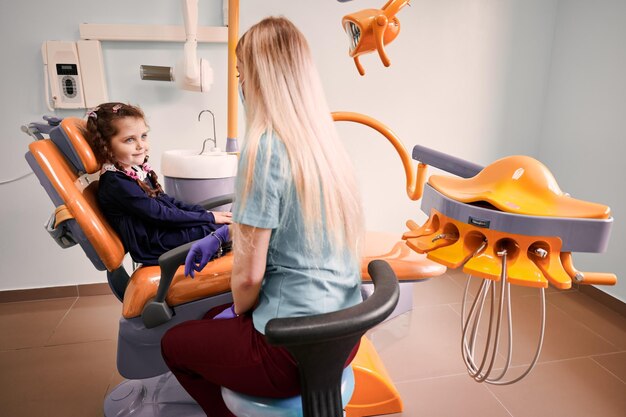치과 사무실에서 어린 소녀와 이야기 하는 소아 치과 의사