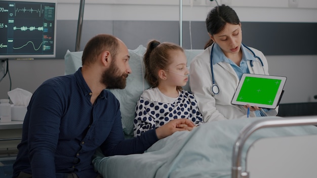 Pediatric woman doctor holding mock up green screen chroma key tablet with isolated display