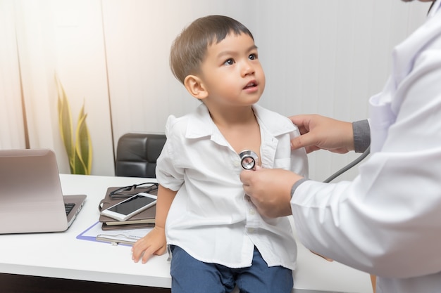 Pediatrician doctor examining a little asian boy by stethoscope
