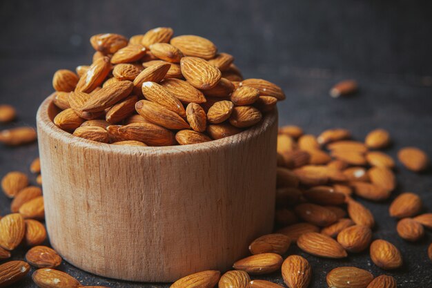 Peeled almonds in a wooden bowl on a dark table