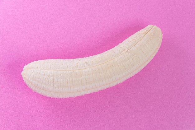 Очищенный банан на розовой поверхности