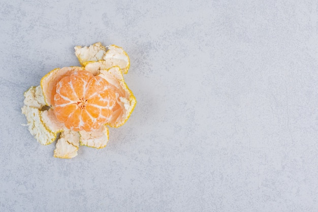 Peeled fresh tangerine on grey background. 