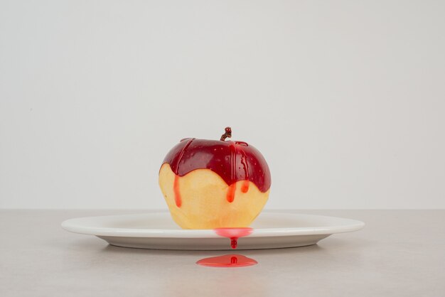 Peeled red apple on white plate.