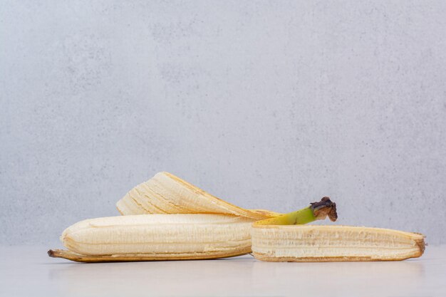 Peeled single banana on white table.