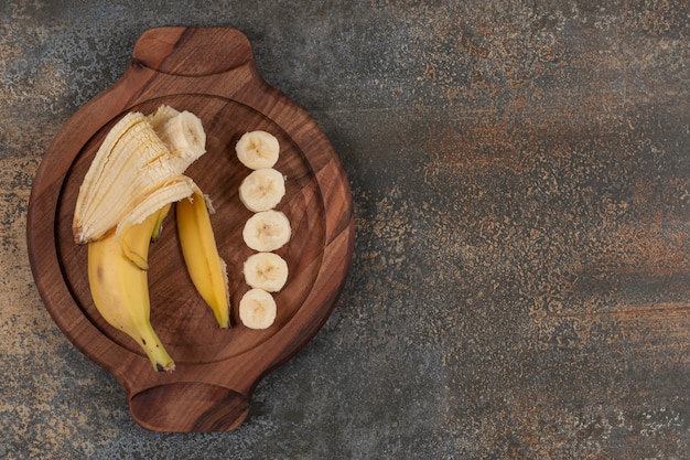 Peeled and sliced banana on wooden board