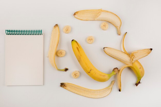 Peeled and sliced bananas on white background with a receipt book aside