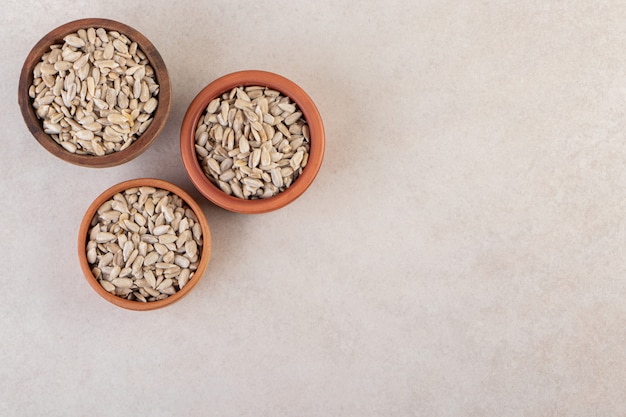 Peeled sunflower seeds in bowl placed on beige table.