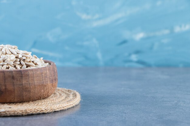 Peeled sunflower seeds in a bowl on the trivet , on the marble background.