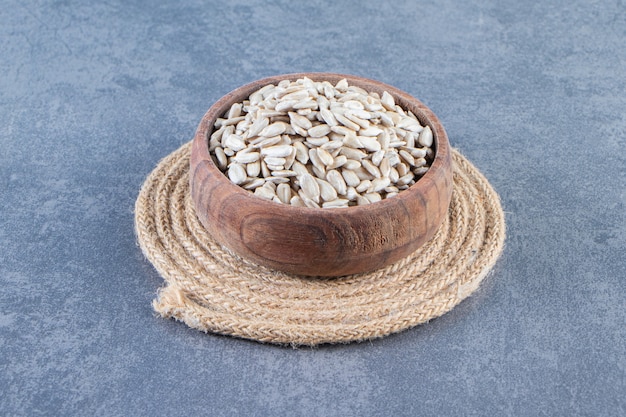 Peeled sunflower seeds in a bowl on the trivet , on the marble background.