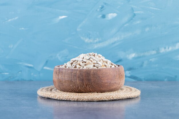 Peeled sunflower seeds in a bowl on the trivet on the marble surface