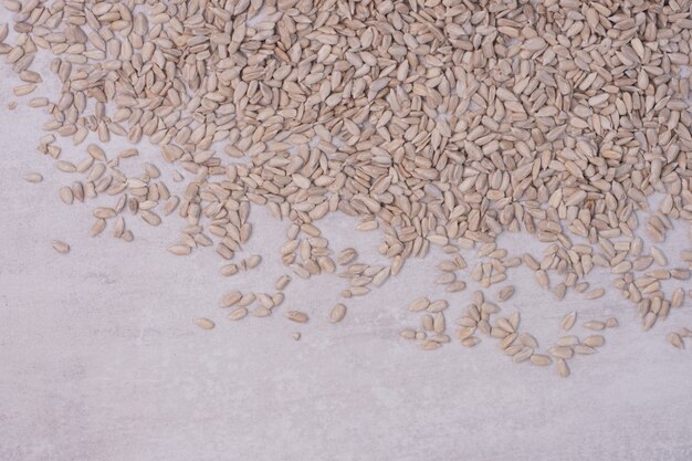 Peeled sunflower seeds on white surface.