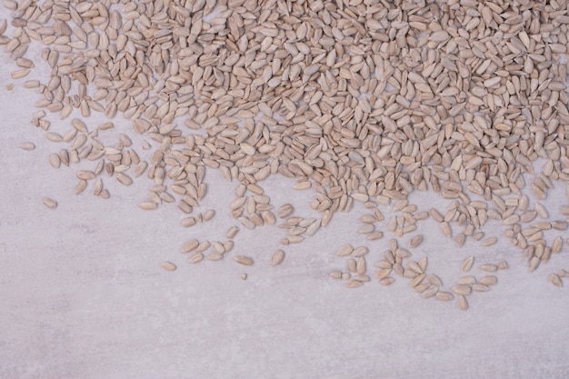 Peeled sunflower seeds on white surface.