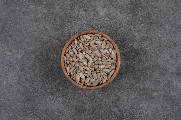 Peeled sunflower seeds in wooden bowl. Top view.