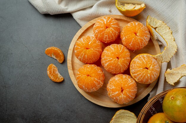 Peeled tangerines on old dark background