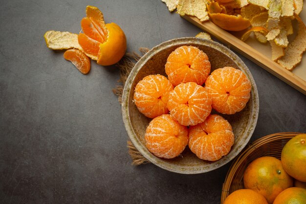 Peeled tangerines on old dark background