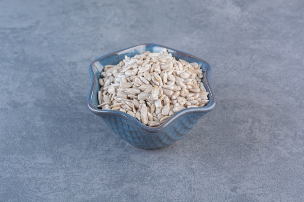 Peeled, tasty sunflower seeds in bowl, on the marble surface