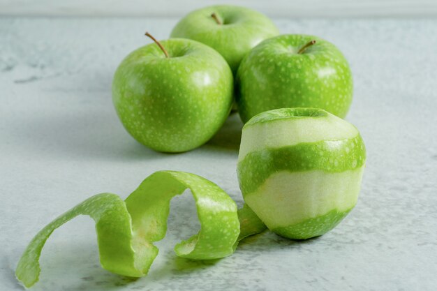 Peeled and Whole fresh organic green apples on grey surface