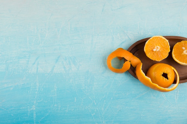 Peeled yellow oranes in a wooden platter, in the right side