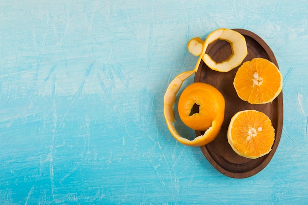 Peeled yellow oranes in a wooden platter, top view