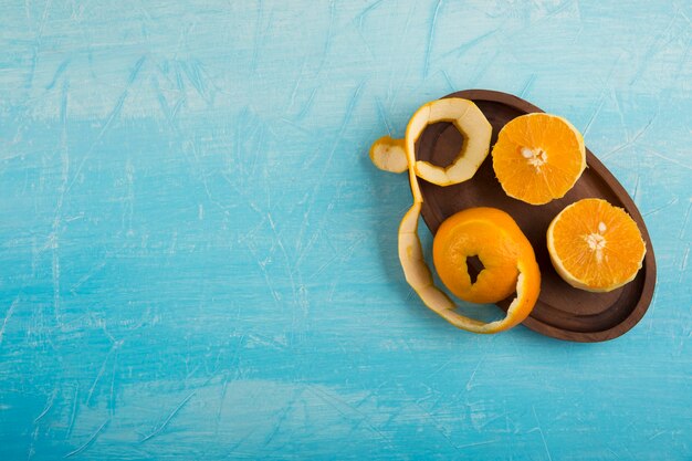 Peeled yellow oranes in a wooden platter, top view