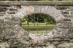 Foto gratuita peep hole con sbarre di ferro su una recinzione in pietra