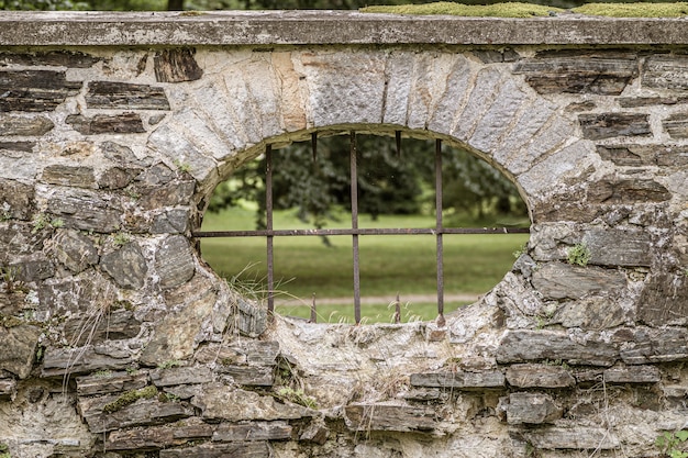 Peep hole with iron bars on a stone fence