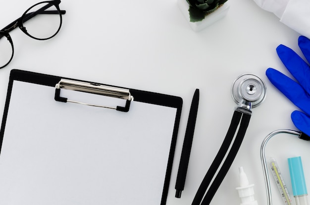 Ручка; бумага в буфер обмена; очки; перчатки и медицинское оборудование на белом фоне